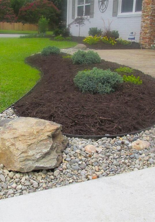 Mulch (Medium) Landscaping installed in front of a home with river rock, mulch, and plants.